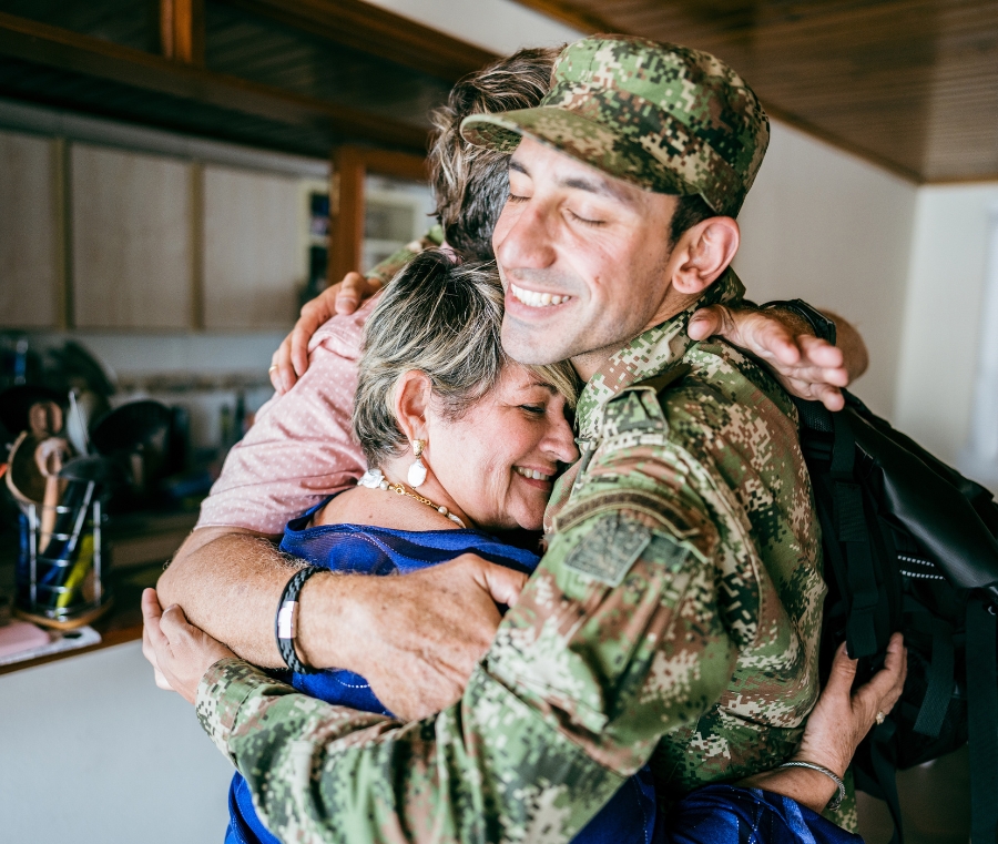 A returning soldier hugs his family, illustrating the military background of the financial advisors at Four Lights, who provice money management for the military and veterans.